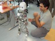 A picture of iCub standing by a human